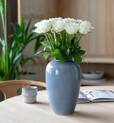 Hvit rosebukett med blå vase